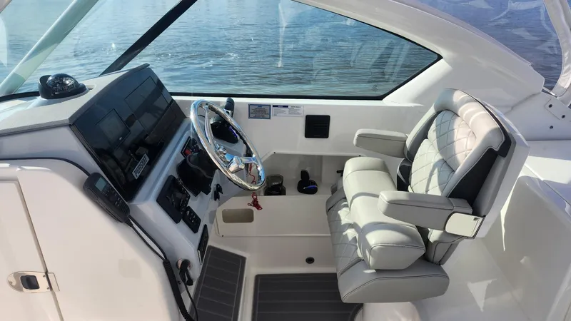  Yacht Photos Pics 2024 Pursuit DC 266 Dual Console boat interior with steering wheel and cushioned seat.