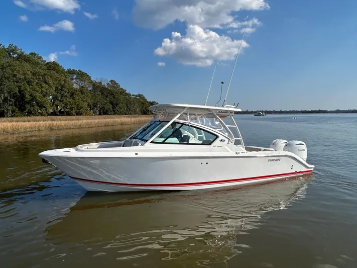  Yacht Photos Pics 2024 Pursuit DC 266 Dual Console boat on calm water under blue sky.