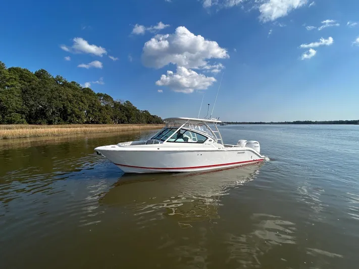  Yacht Photos Pics 2024 Pursuit DC 266 Dual Console boat on calm water under blue sky.