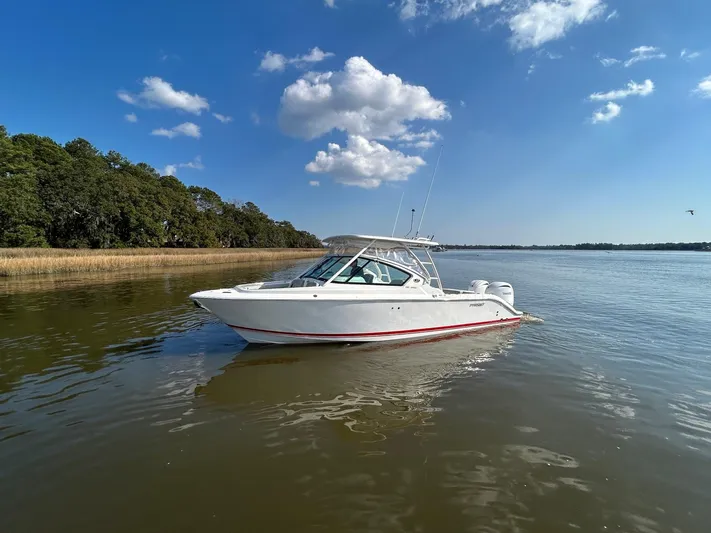  Yacht Photos Pics 2024 Pursuit DC 266 Dual Console boat on calm water under a clear blue sky.