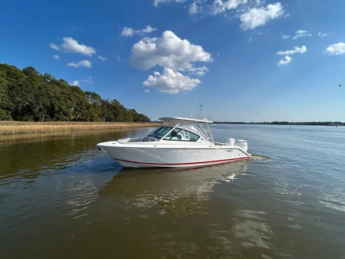  Yacht Photos Pics 2024 Pursuit DC 266 Dual Console boat on calm water under blue sky.