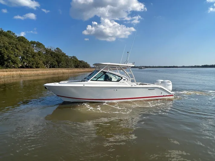 Yacht Photos Pics 2024 Pursuit DC 266 Dual Console boat cruising on a calm river under a clear blue sky.