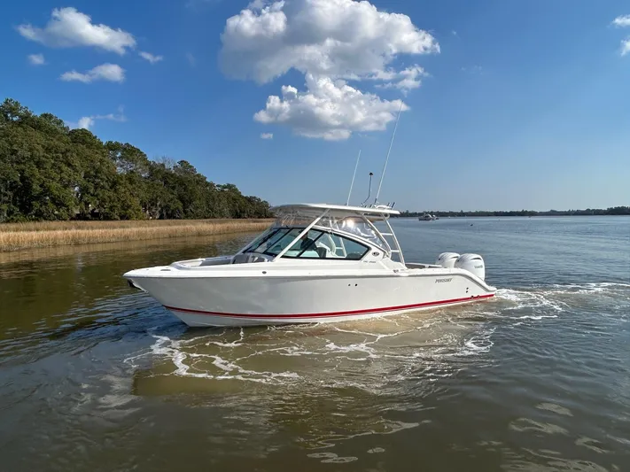  Yacht Photos Pics 2024 Pursuit DC 266 Dual Console boat cruising on a calm lake under a clear blue sky.