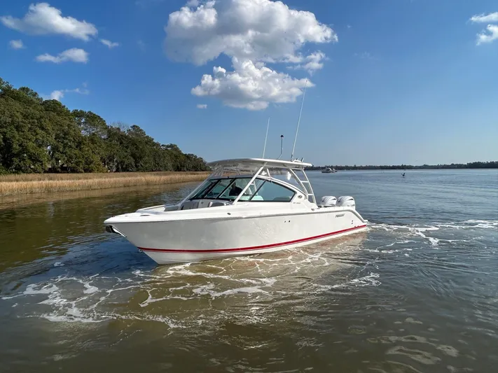  Yacht Photos Pics 2024 Pursuit DC 266 Dual Console boat cruising on a calm lake under a clear blue sky.