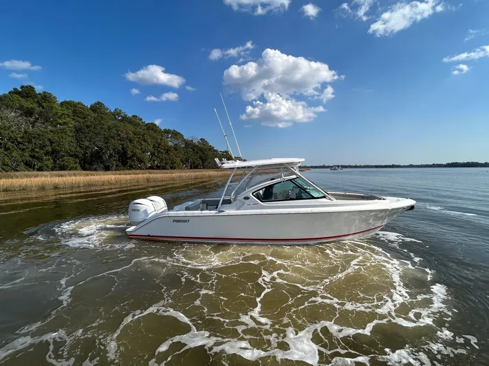  Yacht Photos Pics 2024 Pursuit DC 266 Dual Console boat cruising on a calm lake under a clear blue sky.