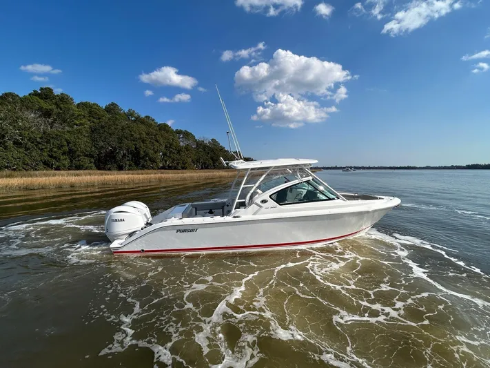  Yacht Photos Pics 2024 Pursuit DC 266 Dual Console boat cruising on a calm lake under a clear blue sky.