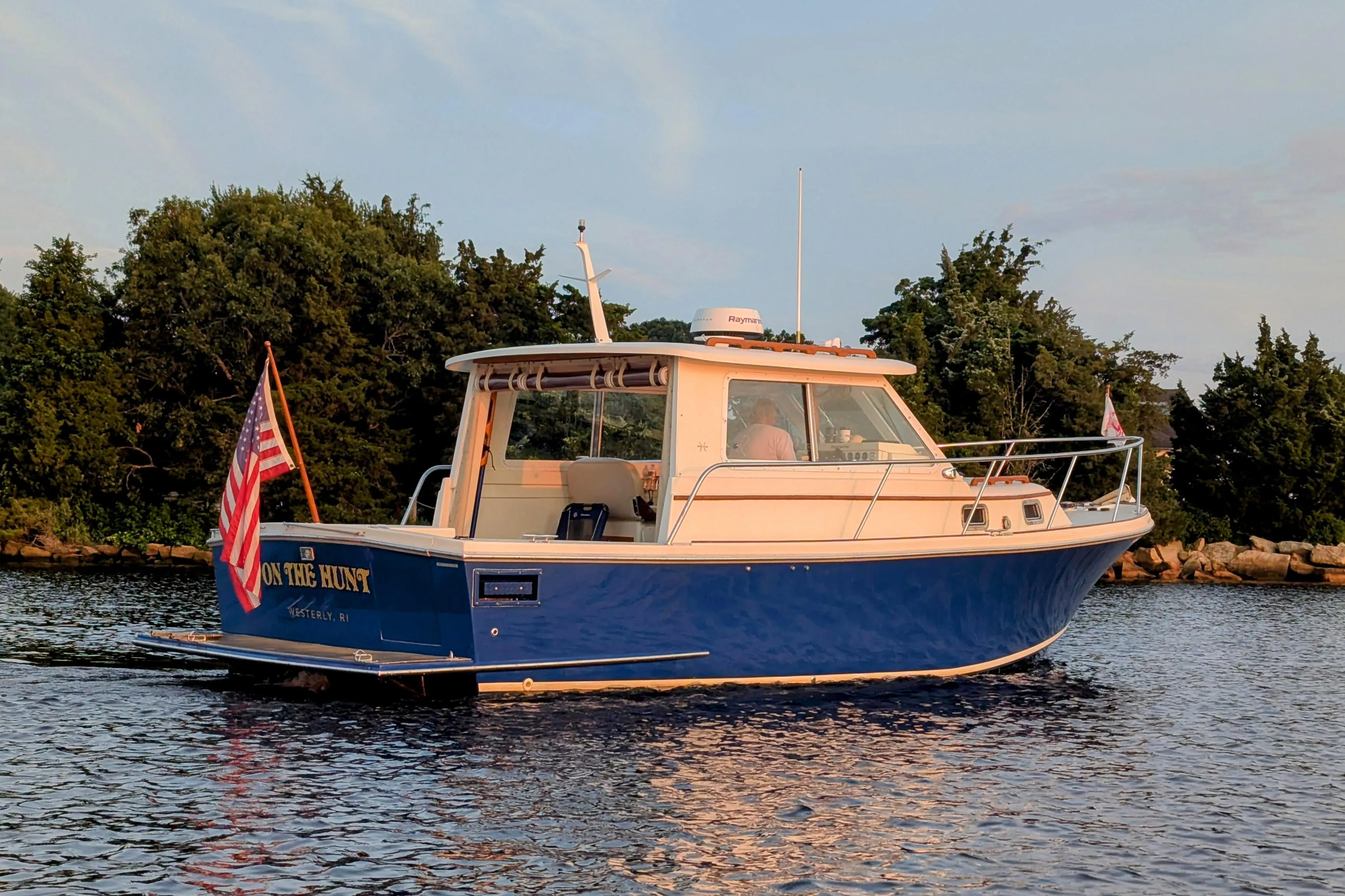 2000 Hunt Yachts 28 Express boat on water, American flag, trees in background.