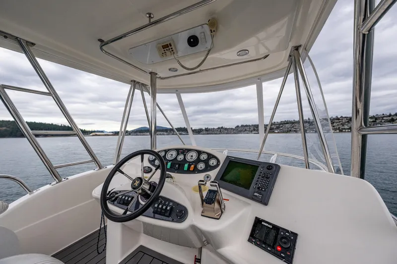  Yacht Photos Pics 2004 Riviera 37 Flybridge helm with navigation equipment, steering wheel, and scenic water view.