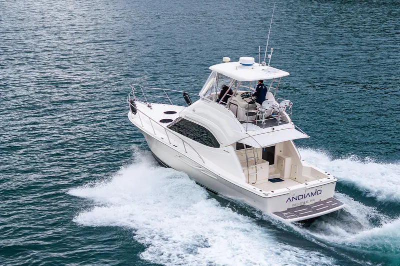  Yacht Photos Pics 2004 Riviera 37 Flybridge yacht cruising on open water, rear view.