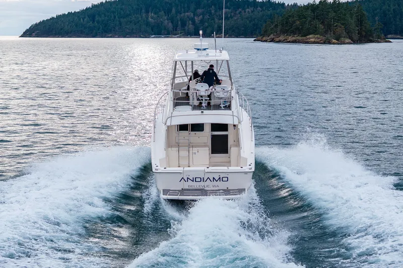  Yacht Photos Pics 2004 Riviera 37 Flybridge cruising on open water near forested islands.