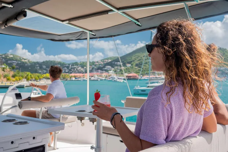 Southern Queen Yacht Photos Pics Woman enjoying a drink on a 2022 Bali 5.4 yacht, scenic coastal view.