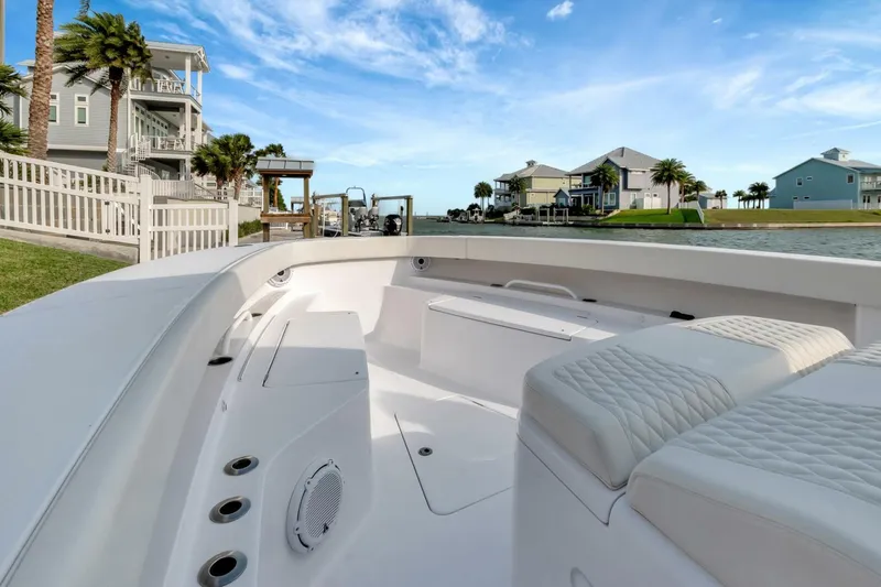 Aqua Toy Yacht Photos Pics 2023 Jupiter 43 Center Console boat docked near waterfront homes under a blue sky.