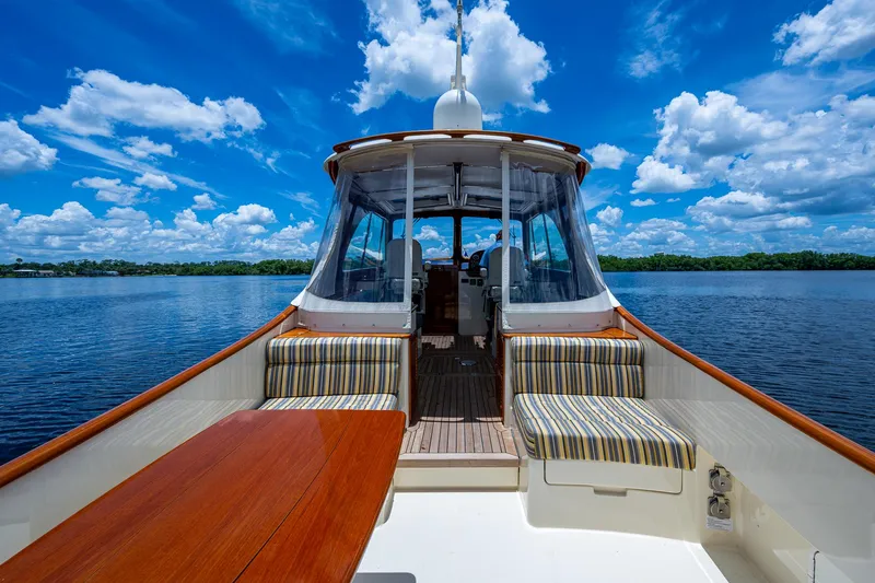 Norora Yacht Photos Pics 2016 Hinckley Picnic Boat 37 MKIII on serene water, featuring striped seating and wooden table.
