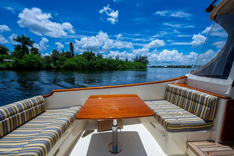 Norora Yacht Photos Pics Hinckley Picnic Boat 37 MKIII, 2016, with striped seating and wooden table, on a scenic river.