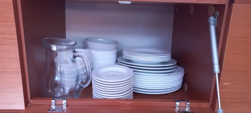 Pelican Yacht Photos Pics Cabinet with neatly stacked white dishes and a glass pitcher on a Dufour 460 Grand Large yacht.