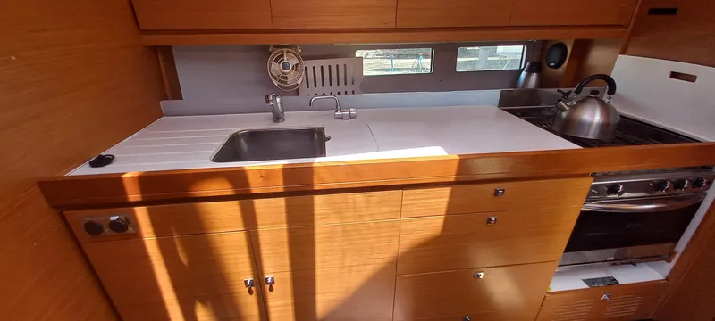 Pelican Yacht Photos Pics Modern kitchen in 2020 Dufour 460 Grand Large yacht with sink, stove, and wooden cabinetry.