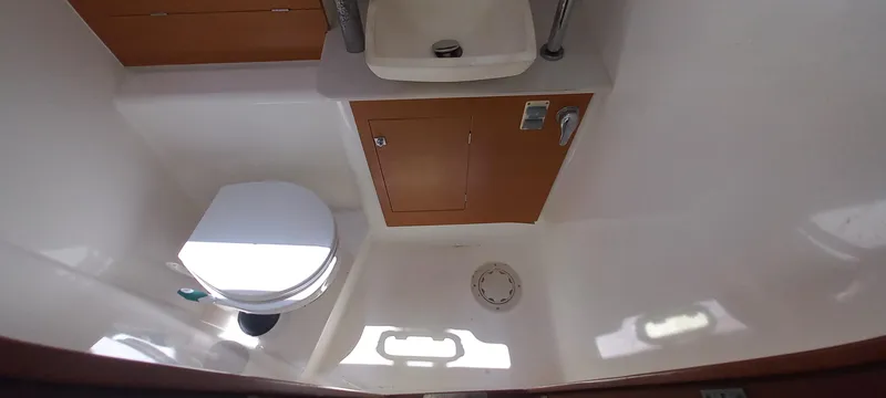 Pelican Yacht Photos Pics 2020 Dufour 460 Grand Large yacht bathroom with toilet, sink, and wooden cabinet.