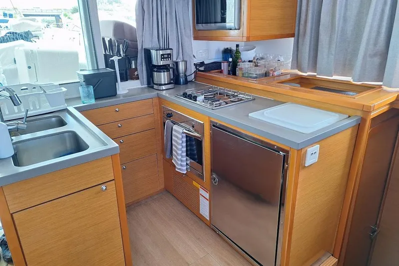 Kala Yacht Photos Pics Modern kitchen interior on a 2016 Lagoon 450 F yacht, featuring wooden cabinetry and stainless steel appliances.
