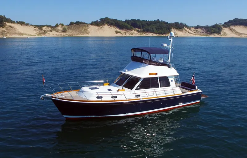 Phoenix Yacht Photos Pics 2014 Grand Banks 46 Eastbay FB yacht cruising on calm waters near sandy shores.