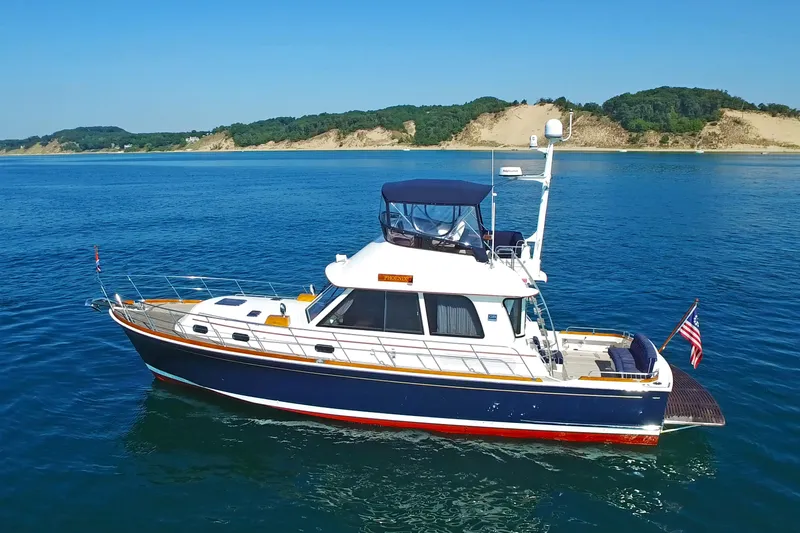 Phoenix Yacht Photos Pics 2014 Grand Banks 46 Eastbay FB yacht on calm blue water, scenic coastline background.