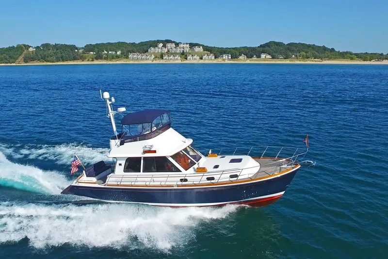 Phoenix Yacht Photos Pics 2014 Grand Banks 46 Eastbay FB cruising on blue water near scenic coastline.