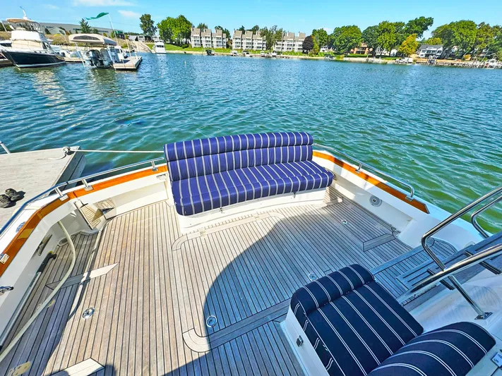 Phoenix Yacht Photos Pics 2014 Grand Banks 46 Eastbay FB yacht with striped seating, docked by a scenic waterfront.