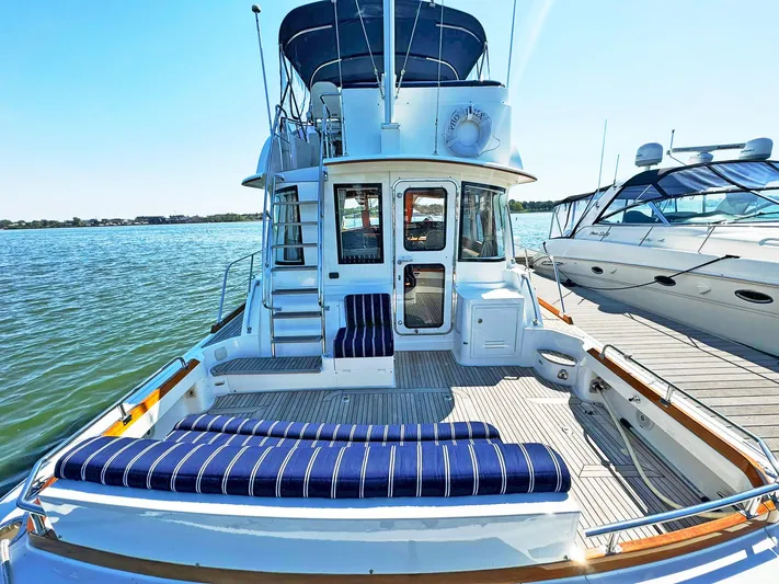 Phoenix Yacht Photos Pics 2014 Grand Banks 46 Eastbay FB yacht with striped seating, docked by the water.