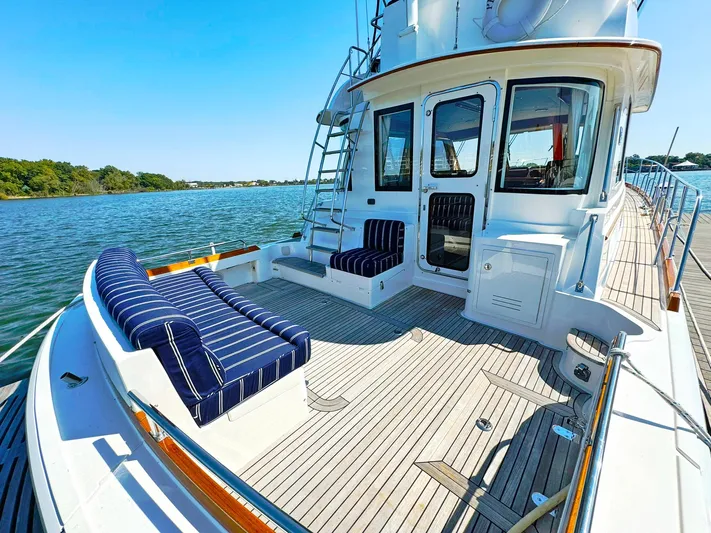 Phoenix Yacht Photos Pics Grand Banks 46 Eastbay FB 2014 yacht with striped seating on deck, docked by calm waters.