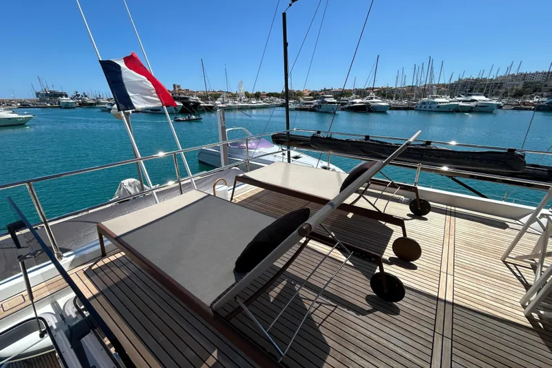  Yacht Photos Pics Deck view of 2022 Prestige X60 yacht in marina, featuring sun loungers and a flag.