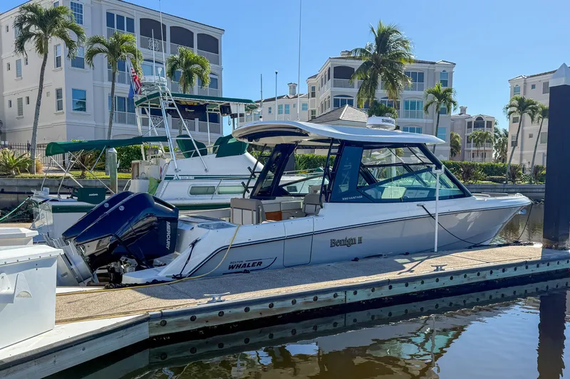  Yacht Photos Pics 2025 Boston Whaler 330 Vantage boat docked, surrounded by palm trees.