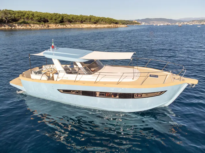  Yacht Photos Pics 2024 Patrone 45 OPEN yacht cruising on clear blue waters near a scenic coastline.
