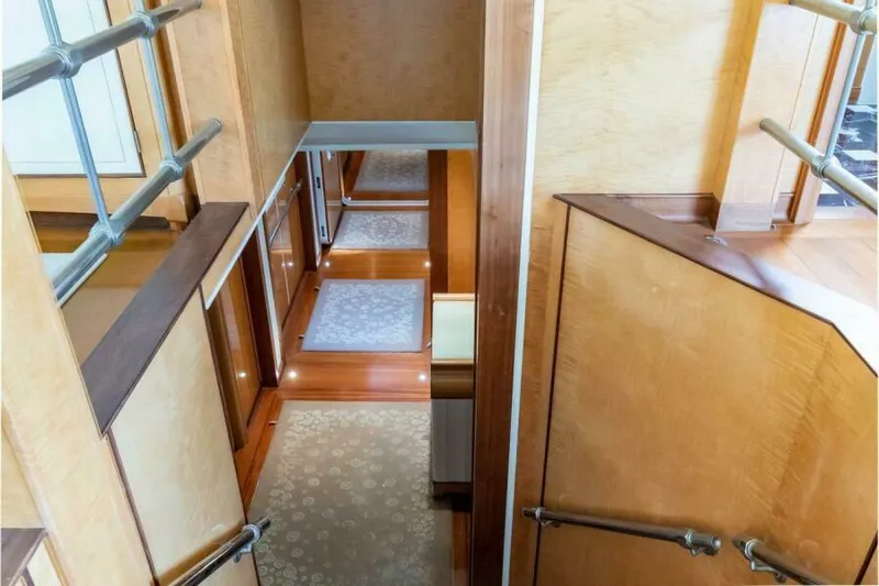  Yacht Photos Pics Luxurious wooden interior of 2004 Pendennis 155 yacht, featuring elegant stairway and carpeted hallway.