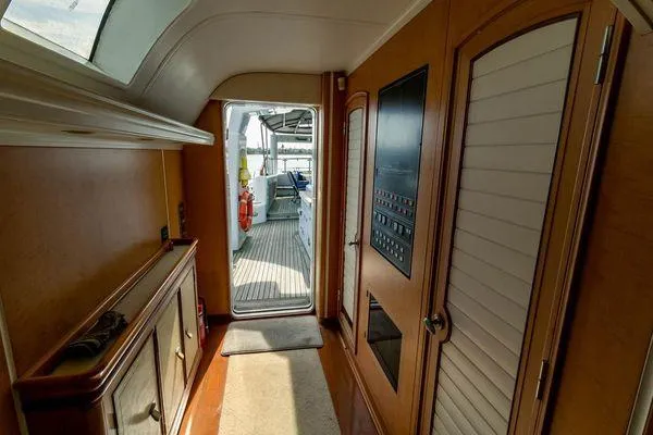  Yacht Photos Pics Interior hallway of 2004 Pendennis 155 yacht with wooden paneling and outdoor view.