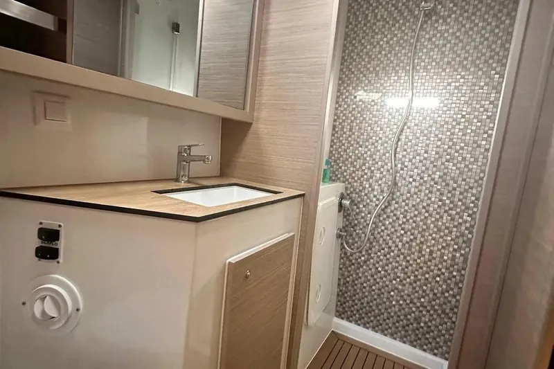 Jack Yacht Photos Pics Modern bathroom in 2024 Lagoon 42 yacht with sleek sink and mosaic-tiled shower.