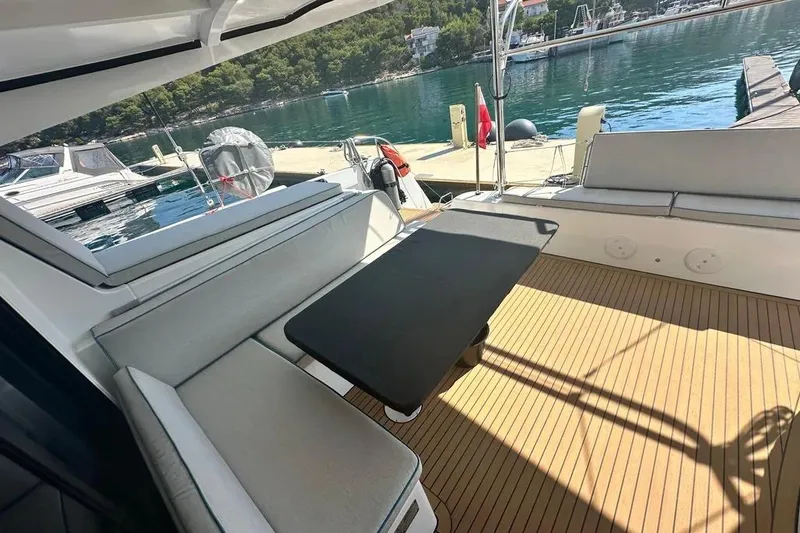 Jack Yacht Photos Pics 2024 Lagoon 42 yacht deck with seating and table, docked by serene waters.