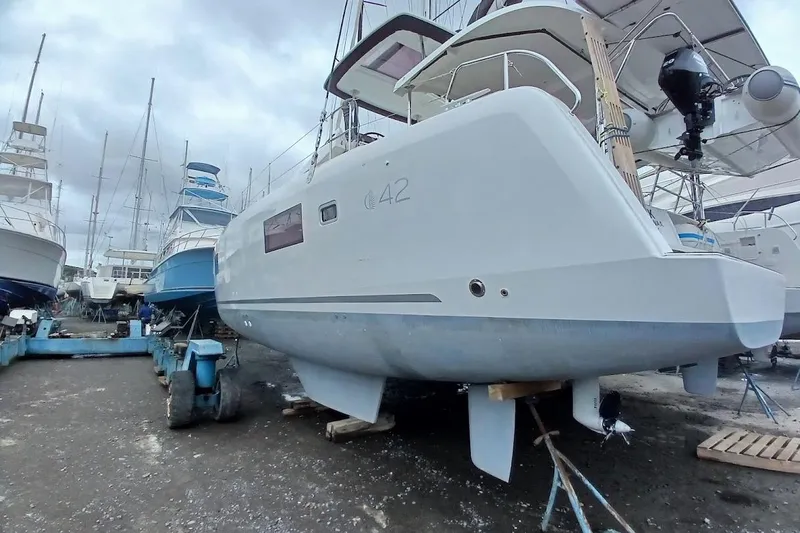 Jack Yacht Photos Pics 2024 Lagoon 42 catamaran in a boatyard, surrounded by other vessels.
