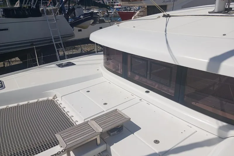 Jack Yacht Photos Pics 2024 Lagoon 42 catamaran deck with netting and seating, docked at marina.