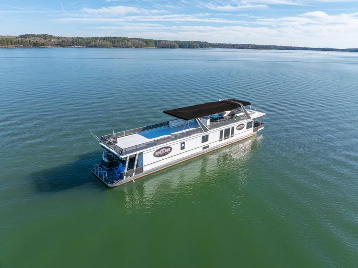  Yacht Photos Pics 1998 Stardust Cruisers Custom Luxury Houseboat on serene lake under clear blue sky.