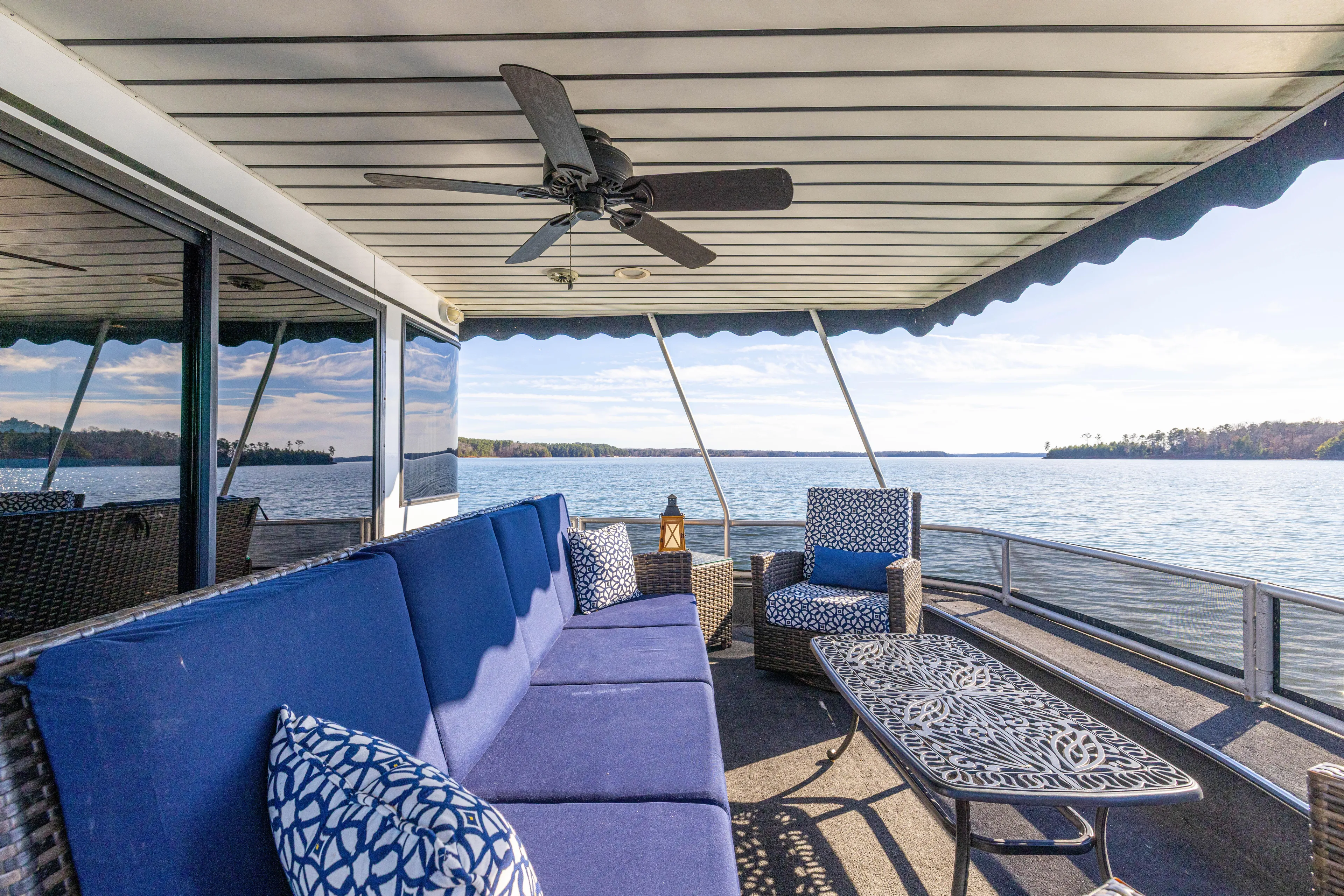  Yacht Photos Pics Luxury houseboat deck with blue seating, ceiling fan, and scenic lake view. Stardust Cruisers 1998 model.