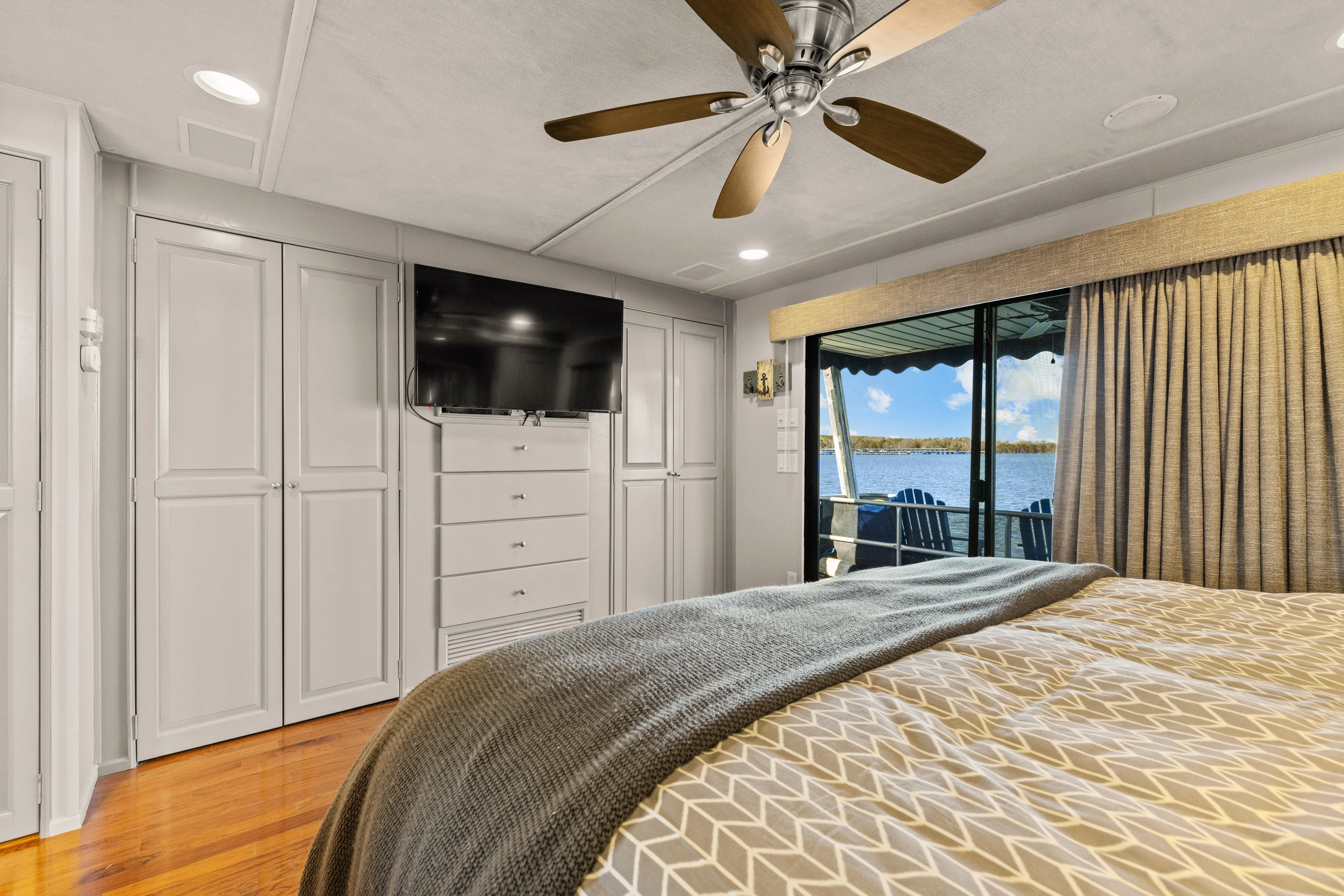  Yacht Photos Pics Luxurious 1998 Stardust Cruisers houseboat bedroom with lake view, TV, and ceiling fan.