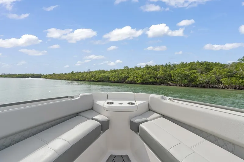  Yacht Photos Pics Bow seating area of 2022 Sea Ray SLX 400 Outboard, overlooking serene water and lush greenery.