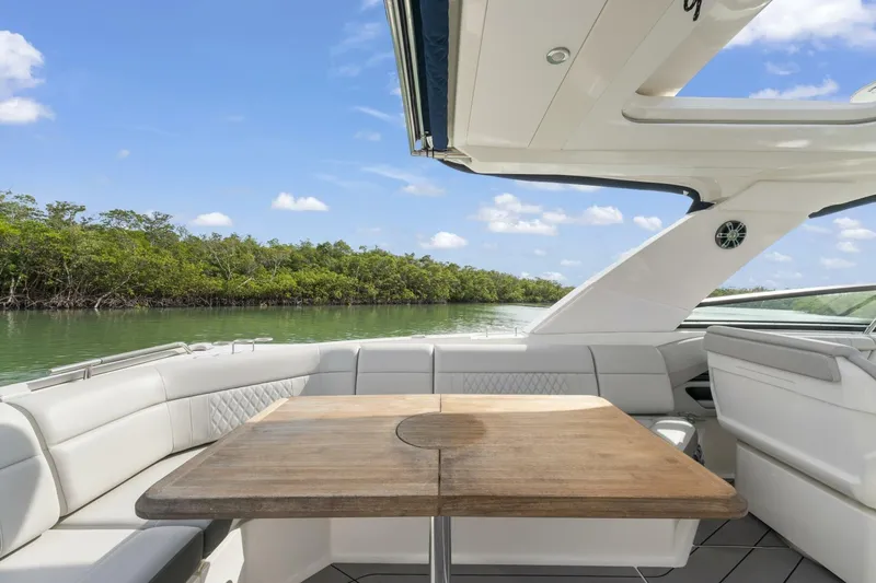  Yacht Photos Pics 2022 Sea Ray SLX 400 Outboard interior with seating and table, surrounded by scenic waterway.