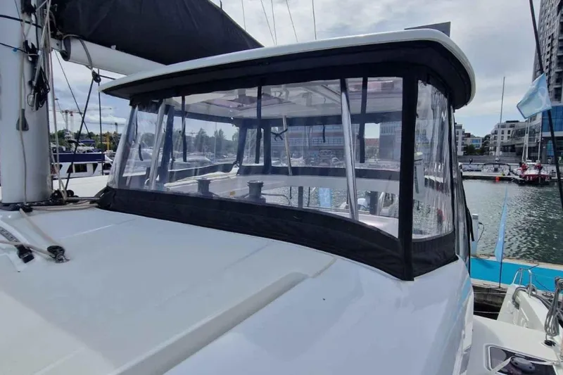  Yacht Photos Pics 2024 Lagoon 42 catamaran with enclosed cockpit, docked in a marina.