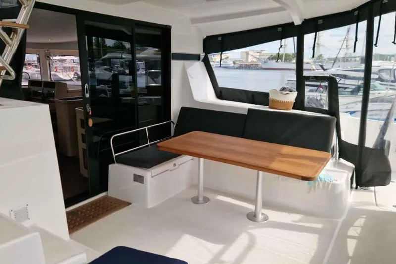  Yacht Photos Pics 2024 Lagoon 42 yacht interior with seating area and wooden table, dockside view.