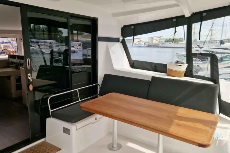  Yacht Photos Pics 2024 Lagoon 42 yacht interior with seating area and wooden table, docked at marina.