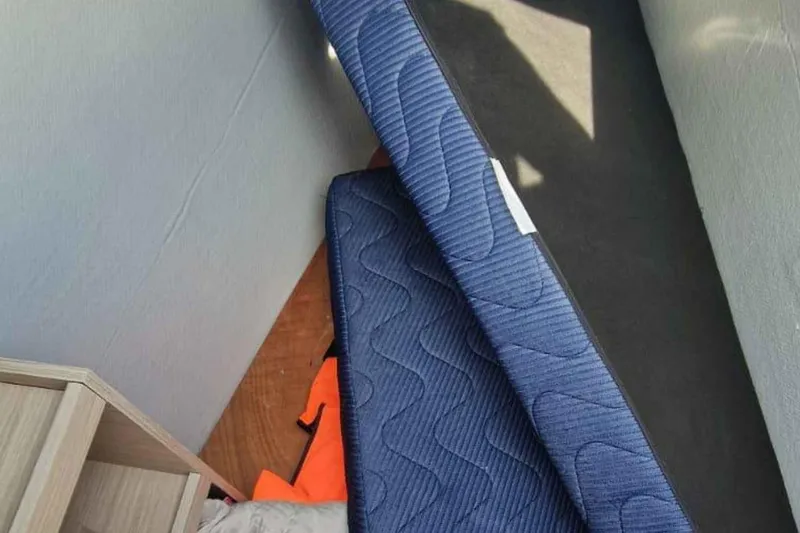  Yacht Photos Pics Interior of 2024 Lagoon 42 showing blue mattress and wooden furniture.