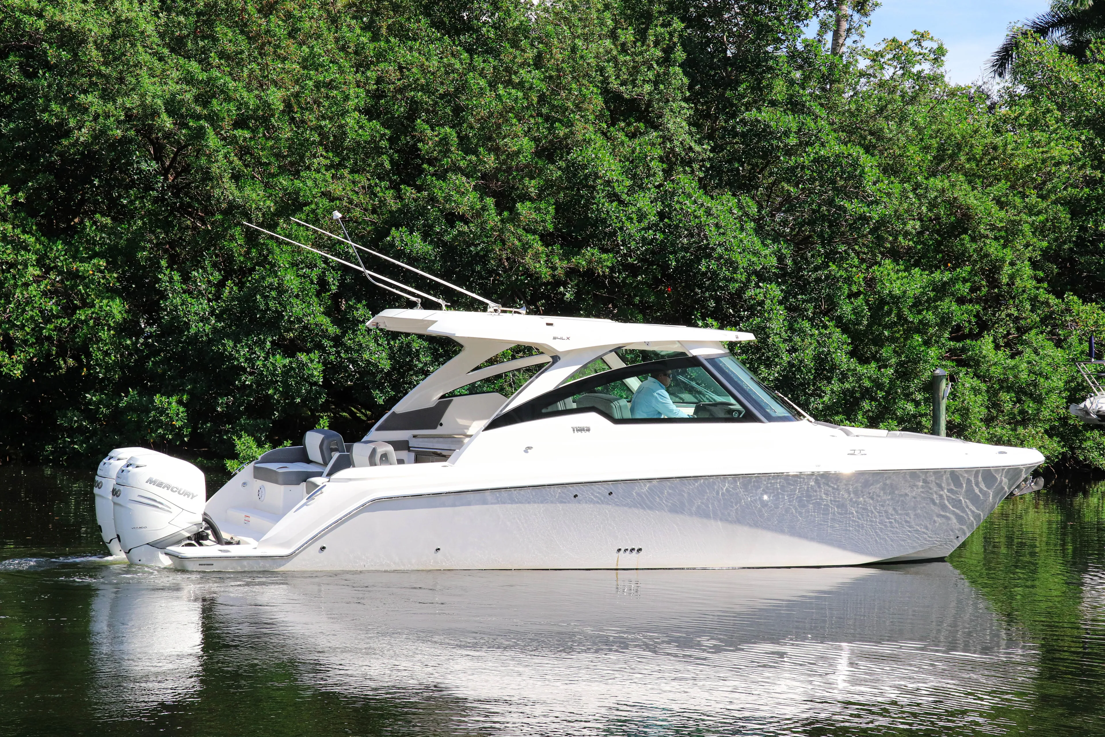  Yacht Photos Pics 2021 Tiara Sport 34 LX boat on a calm river, surrounded by lush greenery.
