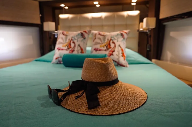 Gigi Yacht Photos Pics Luxurious Azimut 70 yacht bedroom with straw hat and sunglasses on turquoise bed.