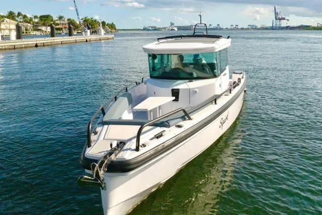 Squirt Yacht Photos Pics 2023 Axopar 28 CABIN boat cruising on a sunny day in a scenic harbor.