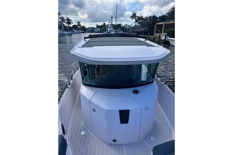 Squirt Yacht Photos Pics 2023 Axopar 28 CABIN boat docked on a calm waterway under a cloudy sky.